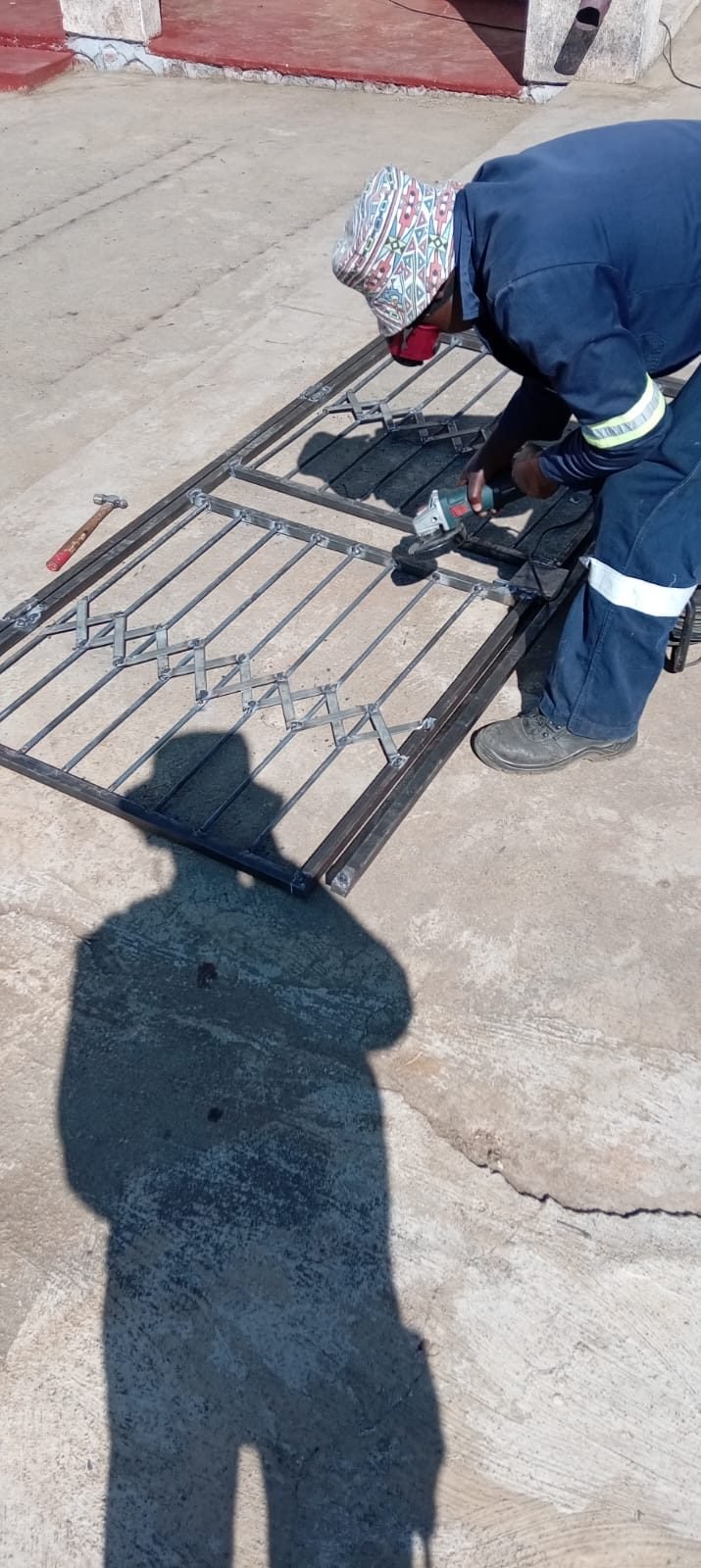 Xolile Makunyane grinding a steel gate in PPE